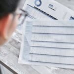 A businesswoman reviewing financial spreadsheets with charts and graphs in an office setting.